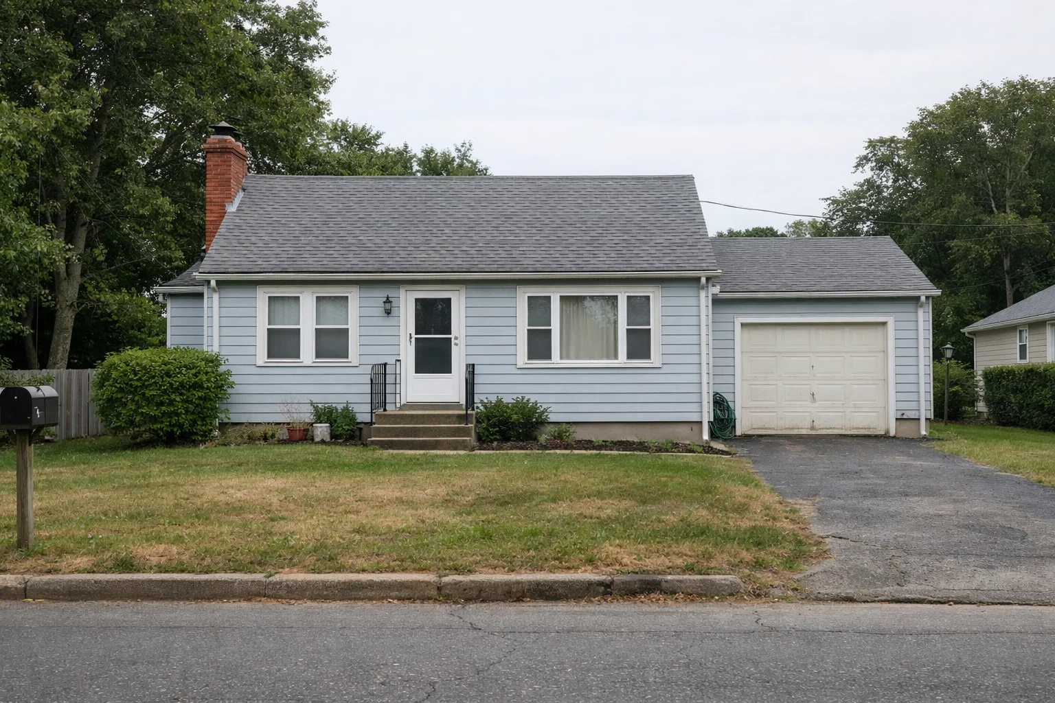Single-story Connecticut home with light blue siding, a detached garage, and a modest front yard, shown from the street in natural daylight.